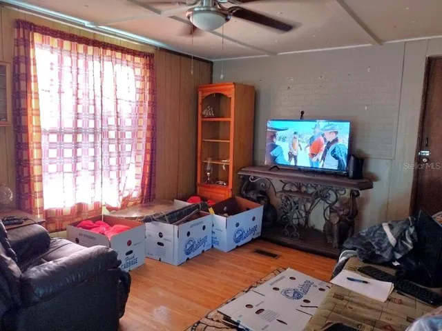 a living room with furniture a flat screen tv and a floor to ceiling window