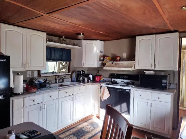 a kitchen with granite countertop a sink stainless steel appliances and white cabinets