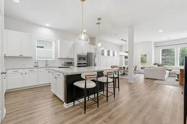 a large white kitchen with lots of counter space dining table and chairs