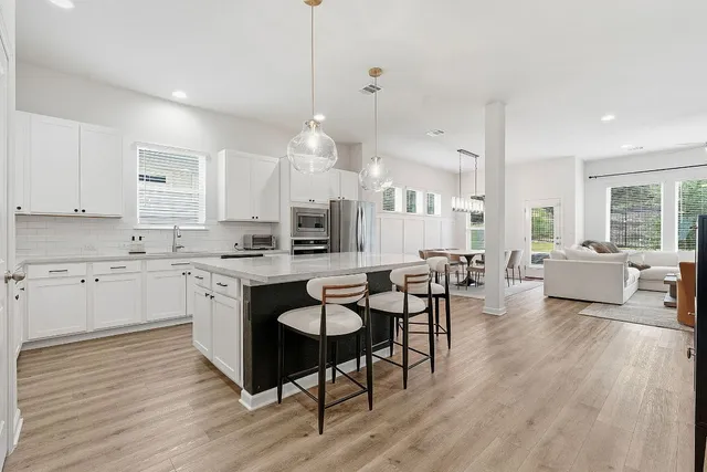 a large white kitchen with lots of counter space dining table and chairs