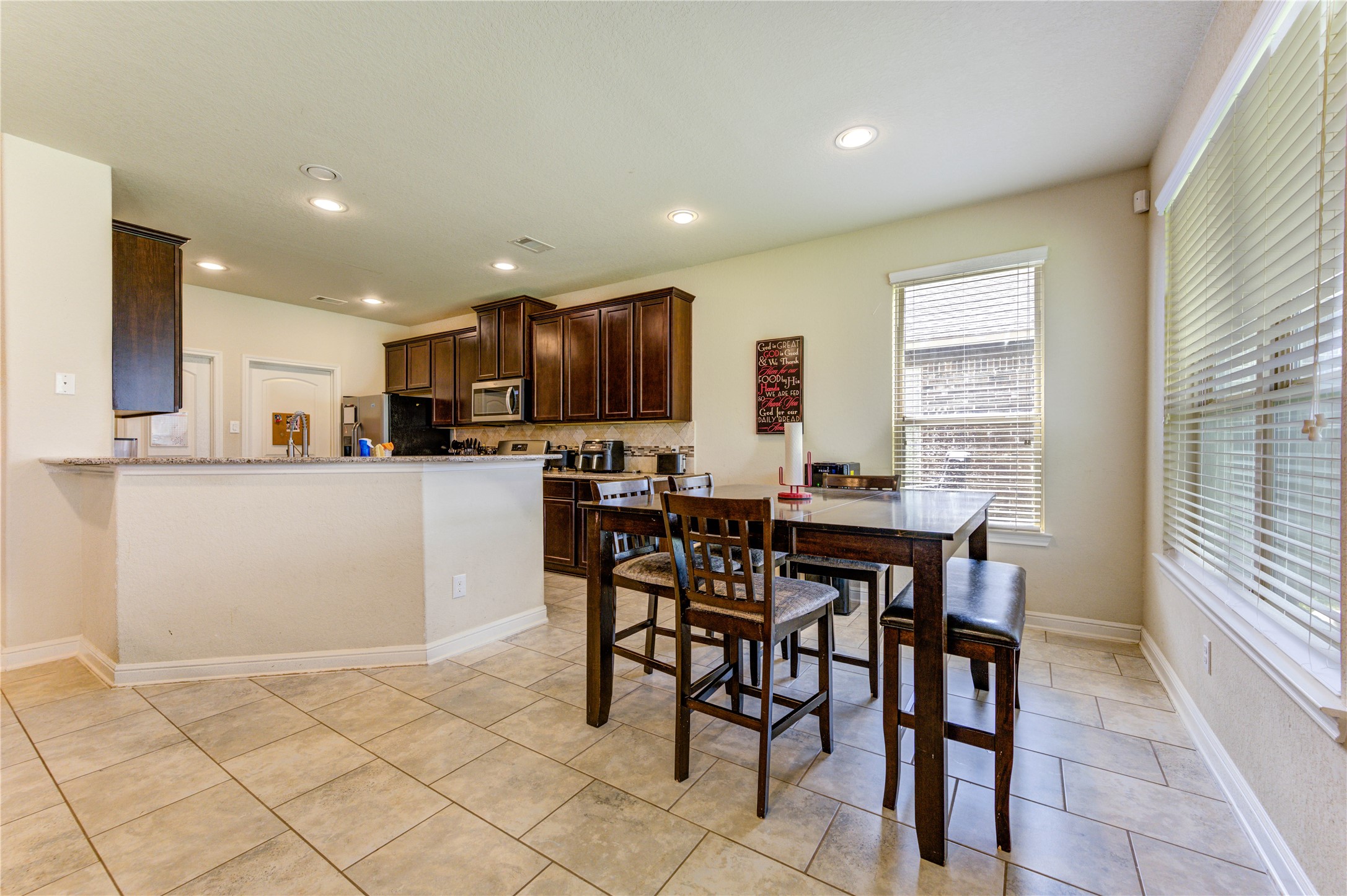 24511 Stratton Creek Drive Spring, TX 77373 - Photo 10 of 27 Heart of the Home – Enjoy seamless connectivity between the living room, breakfast area, and kitchen, all complemented by durable tile flooring and abundant natural light.