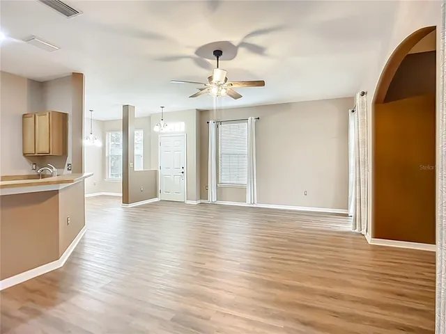 a view of an empty room with window and wooden floor