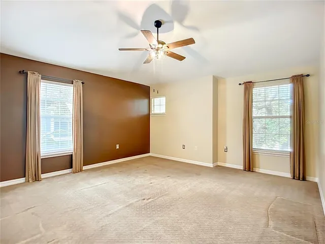 an empty room with fan and windows