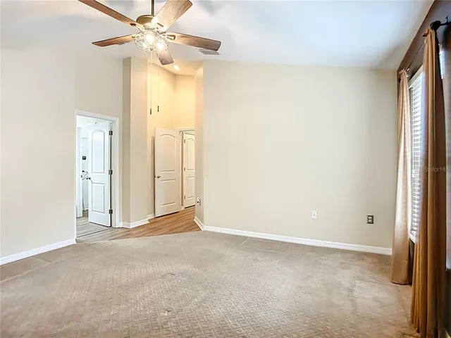 an empty room with closet and a chandelier fan