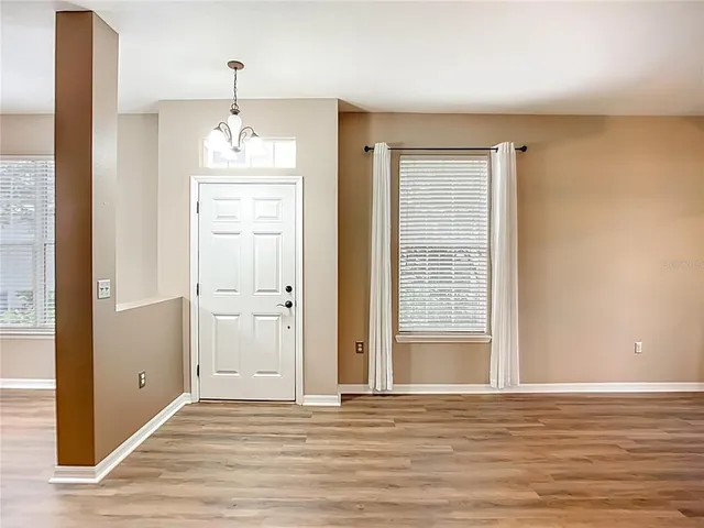 an empty room with wooden floor cabinet and windows