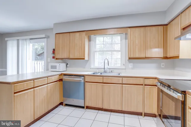 a kitchen with white cabinets appliances a sink and a window