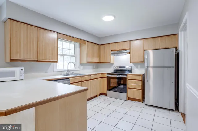 a kitchen with granite countertop a refrigerator sink stove and cabinets