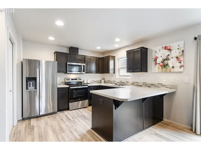 a kitchen with stainless steel appliances kitchen island a sink refrigerator and microwave