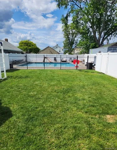 a view of backyard with swimming pool and seating