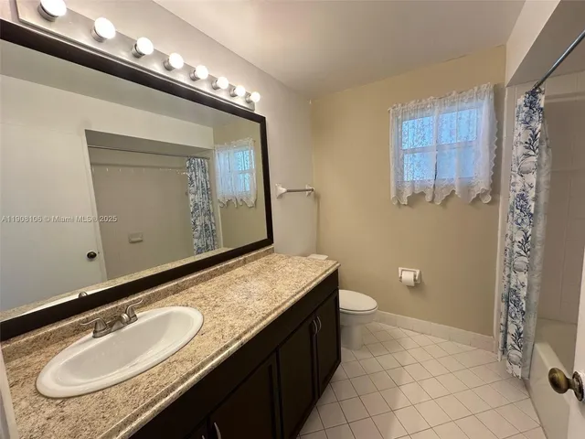 a bathroom with a granite countertop sink a mirror and a toilet