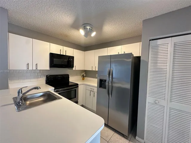 a kitchen with a refrigerator a microwave a sink and cabinets