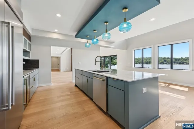 a large kitchen with a large counter top a sink and stainless steel appliances