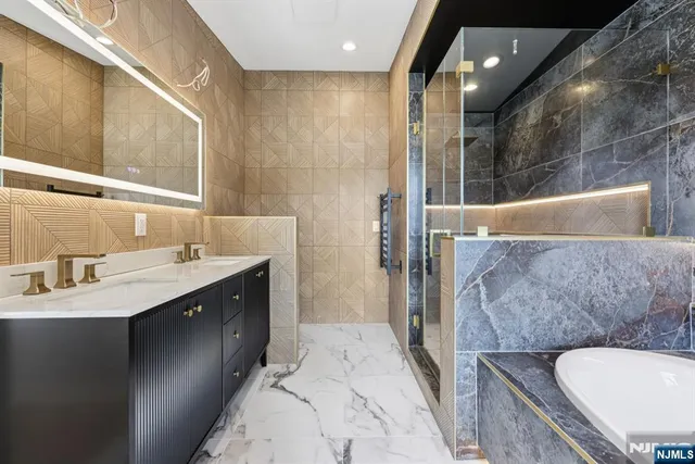 a bathroom with a sink double vanity granite tub shower and a mirror