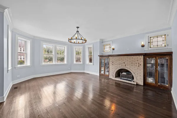 a view of a livingroom with wooden floor a flat screen tv and a exposed radiator with wooden floor