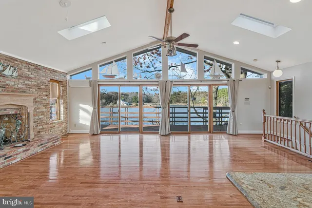a view of an empty room with wooden floor and a large window