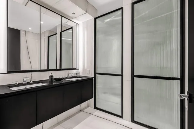 a bathroom with a sink and mirror with shower
