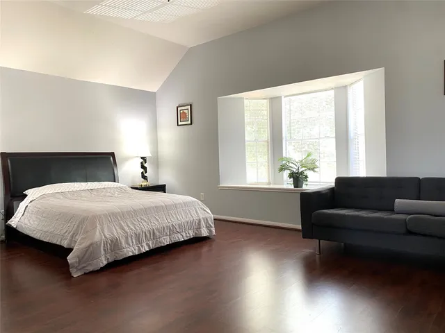 a spacious bedroom with a bed and a couch next to a window