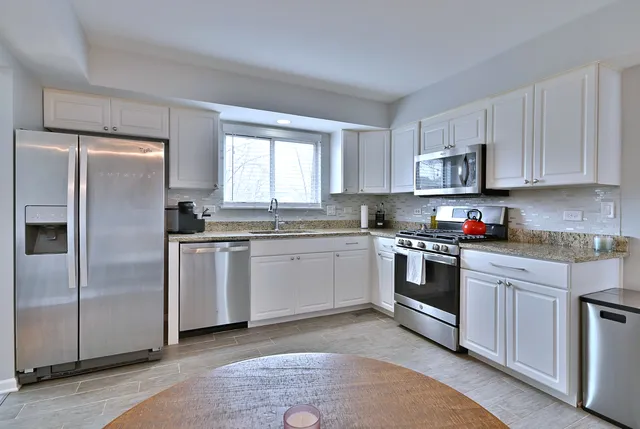 a kitchen with stainless steel appliances granite countertop a stove a sink and a refrigerator