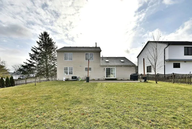 a big house with a large pool and lawn chairs under an umbrella