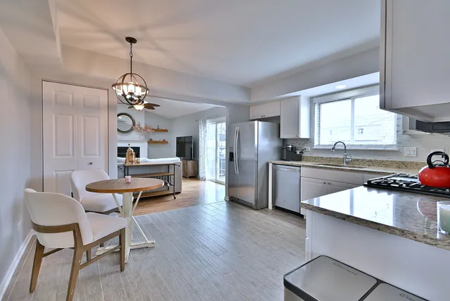 a kitchen with stainless steel appliances kitchen island granite countertop a sink dishwasher a stove a refrigerator and cabinets with wooden floor