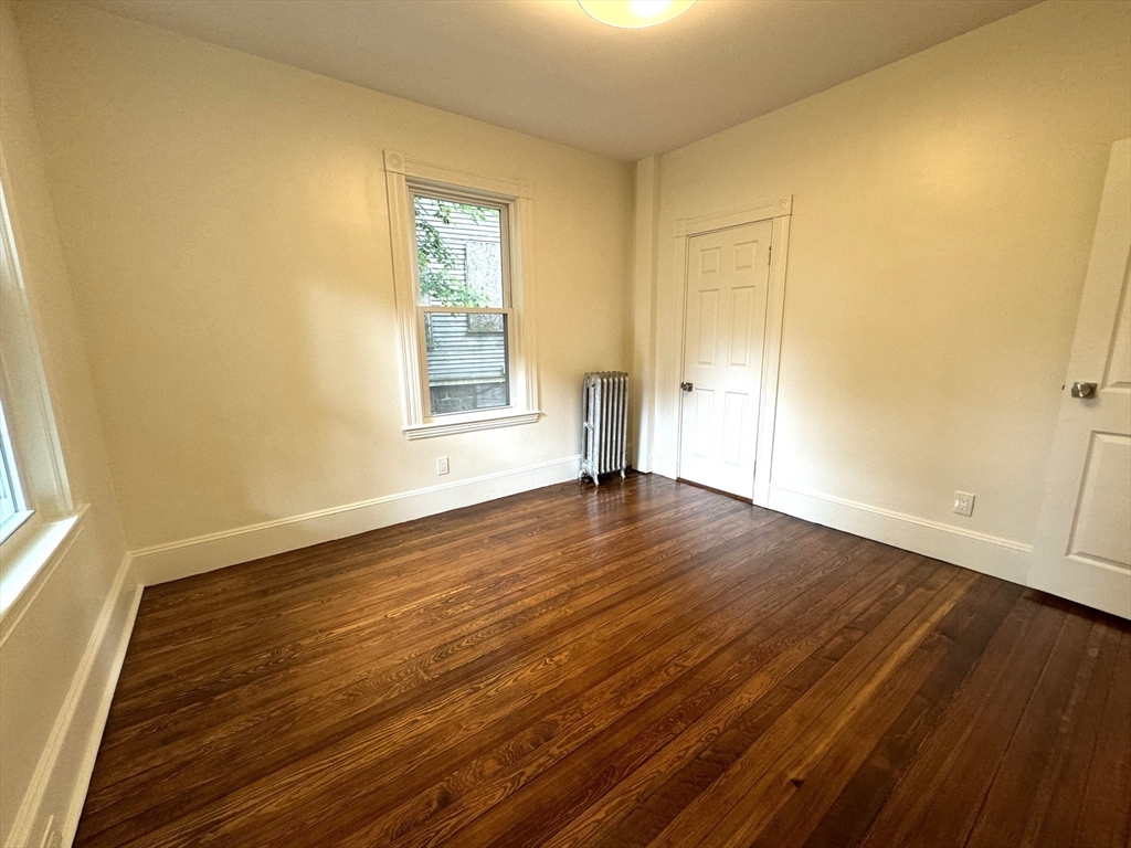 11 East Milton Road, Unit 1 Brookline, MA 02445 - Photo 12 of 24 a view of an empty room with wooden floor and a window