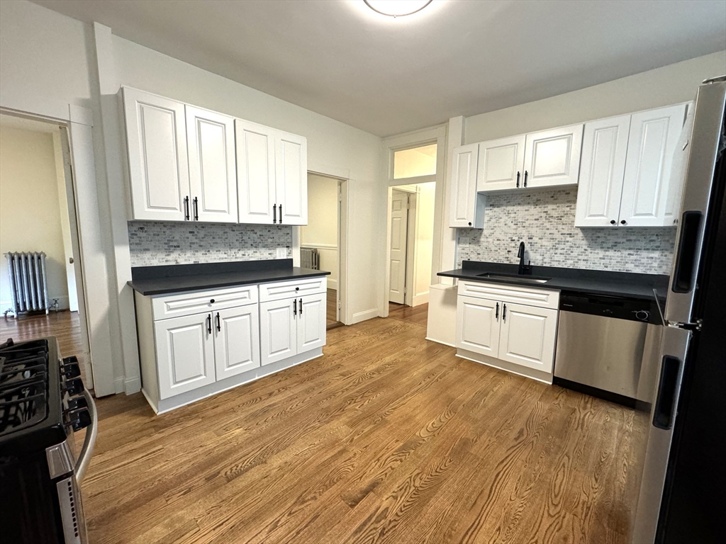 11 East Milton Road, Unit 1 Brookline, MA 02445 - Photo 3 of 24 a large kitchen with stainless steel appliances granite countertop a stove a sink and white cabinets
