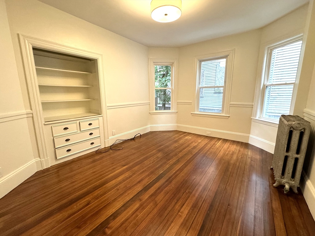 11 East Milton Road, Unit 1 Brookline, MA 02445 - Photo 5 of 24 a view of an empty room with a window and wooden floor