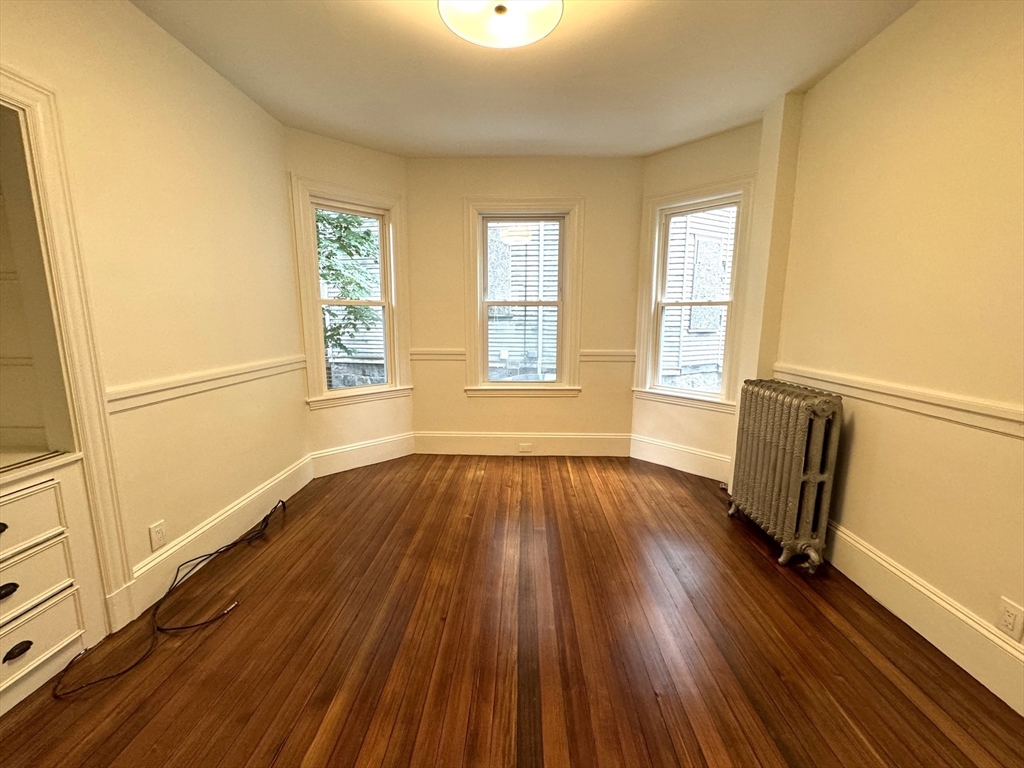 11 East Milton Road, Unit 1 Brookline, MA 02445 - Photo 6 of 24 an empty room with wooden floor and windows