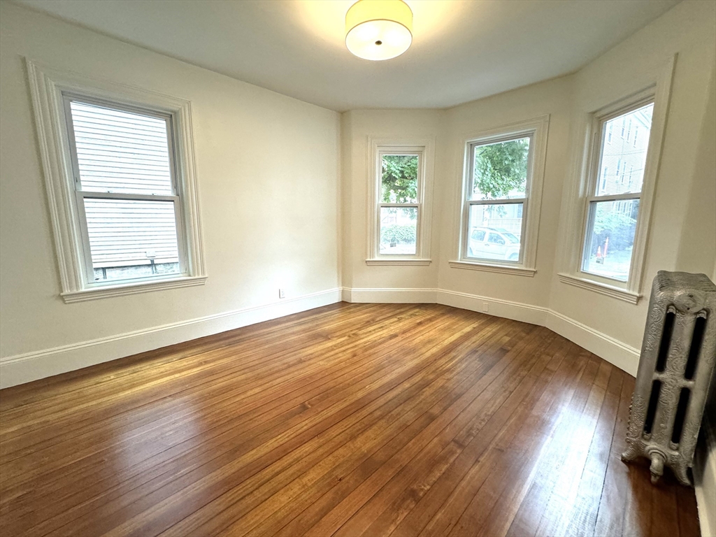 11 East Milton Road, Unit 1 Brookline, MA 02445 - Photo 7 of 24 a view of an empty room with wooden floor and a window