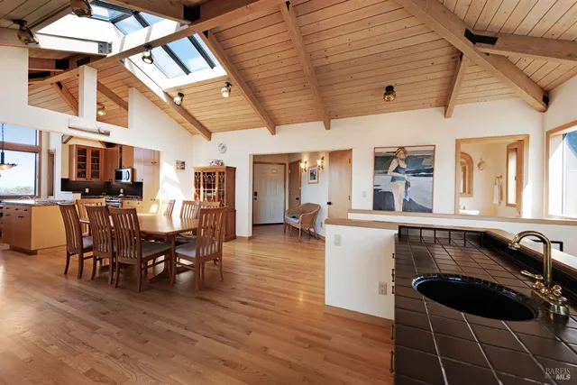 a kitchen with stainless steel appliances granite countertop a refrigerator a sink dishwasher a stove and a dining table with wooden floor