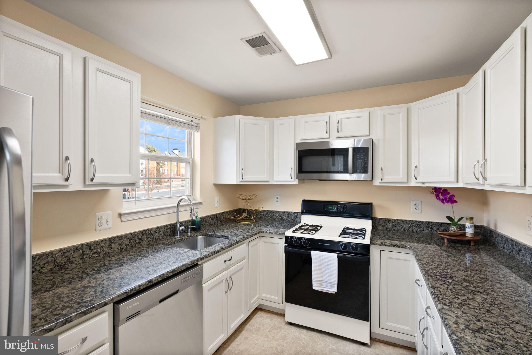 521 Constellation Square Southeast, Unit E Leesburg, VA 20175 - Photo 11 of 27 a kitchen with granite countertop white cabinets appliances and a window