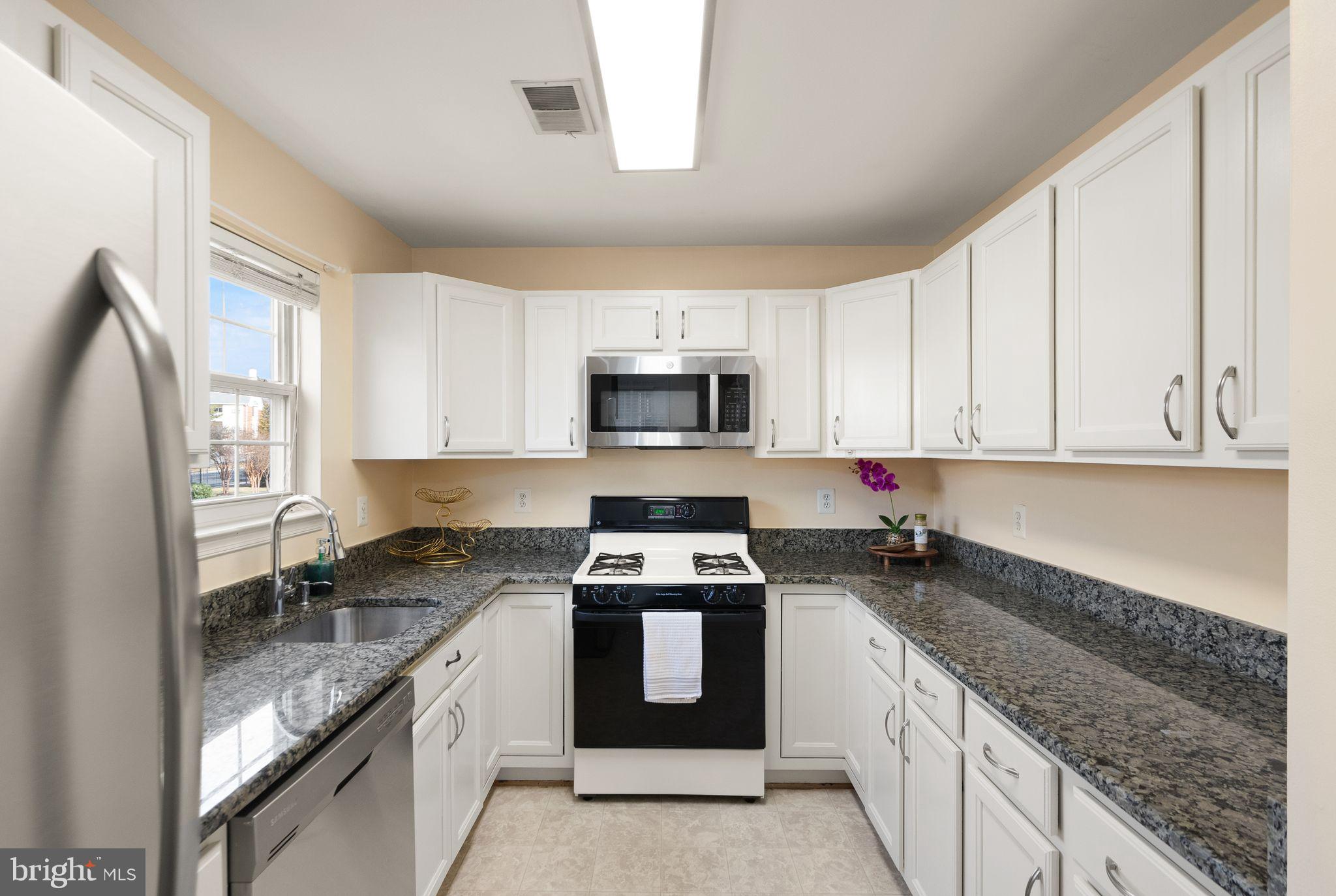 521 Constellation Square Southeast, Unit E Leesburg, VA 20175 - Photo 10 of 27 a kitchen with granite countertop stainless steel appliances a stove a sink a microwave a refrigerator and cabinets