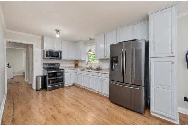 a kitchen with granite countertop a refrigerator cabinets and wooden floor