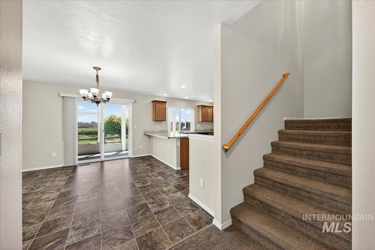 1555 Condor Drive Middleton, ID 83644 - Photo 21 of 50 Open-concept living area with tiled flooring and a carpeted staircase featuring a wood handrail
