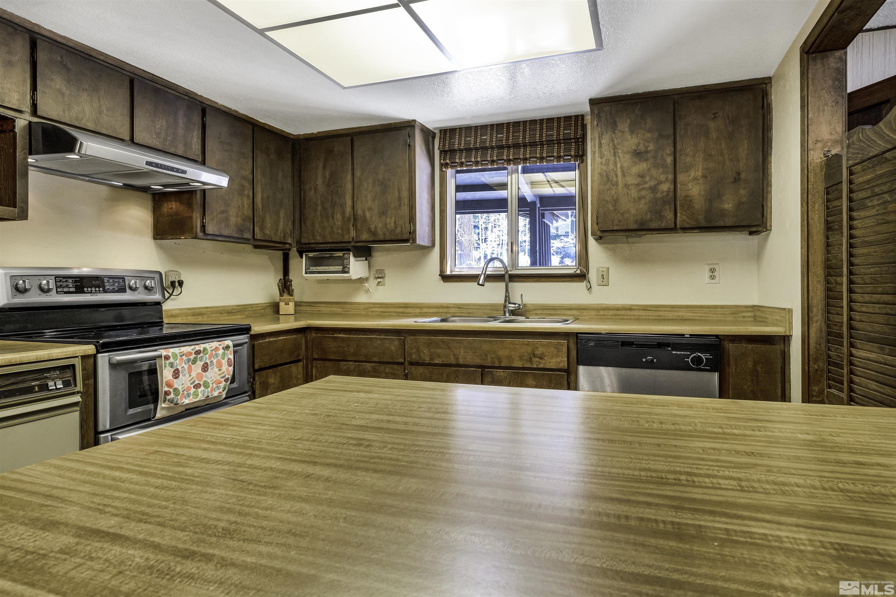 174 Juniper Drive Stateline, NV 89449 - Photo 11 of 32 a kitchen with stainless steel appliances wooden cabinets a stove a sink and a microwave