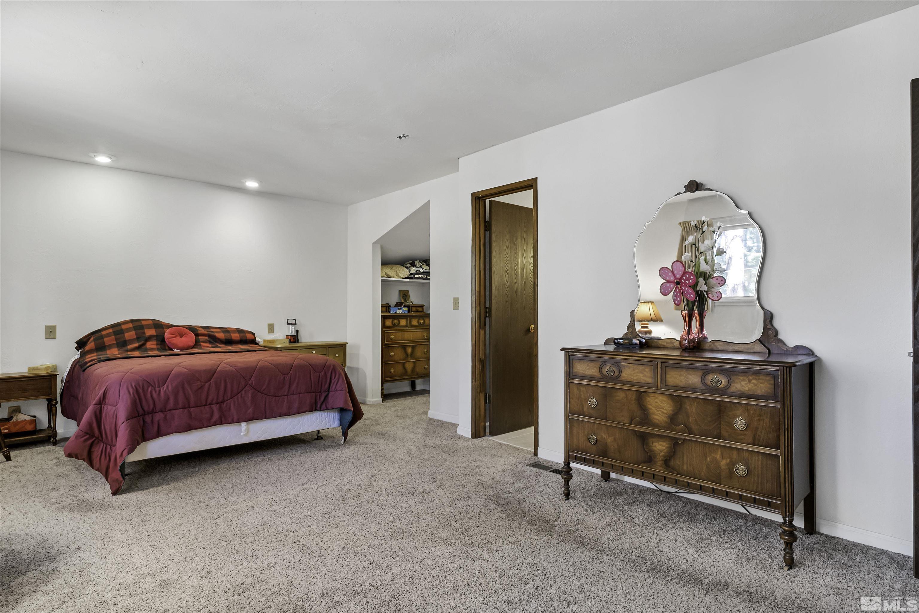 174 Juniper Drive Stateline, NV 89449 - Photo 22 of 32 a spacious bedroom with a bed and a chandelier