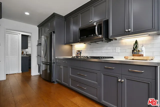 a kitchen with granite countertop a sink cabinets and stainless steel appliances