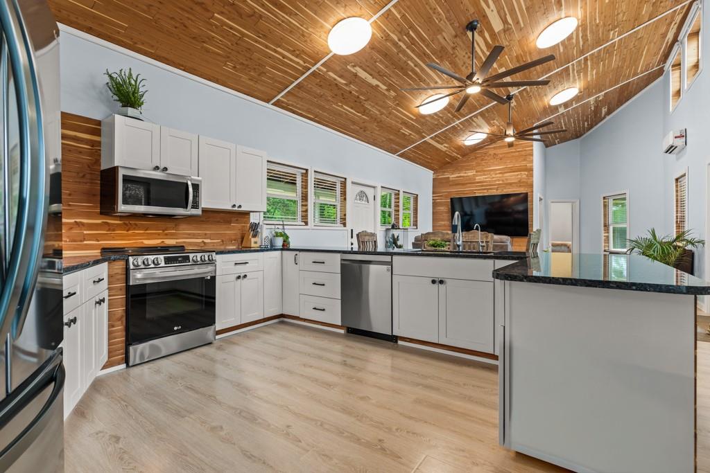 1129 Holly Road Gilmer, TX 75644 - Photo 6 of 31 Kitchen featuring light wood-finish flooring, white cabinetry, dark countertops, and stainless steel appliances
