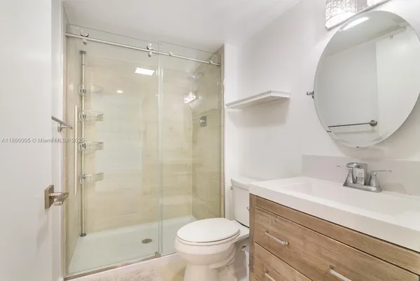 a bathroom with a shower sink vanity mirror and toilet