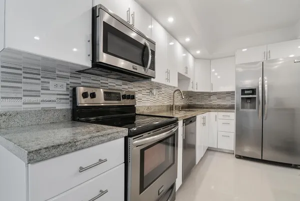 a kitchen with granite countertop a stove microwave and refrigerator