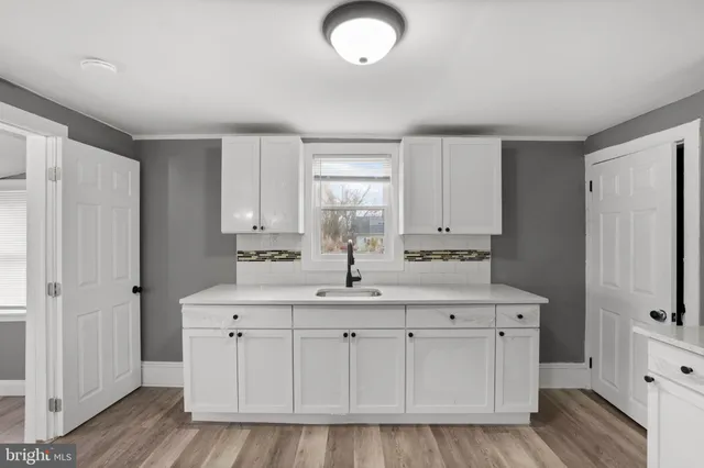 a kitchen with white cabinets and sink