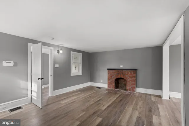 an empty room with fireplace wooden floor and door