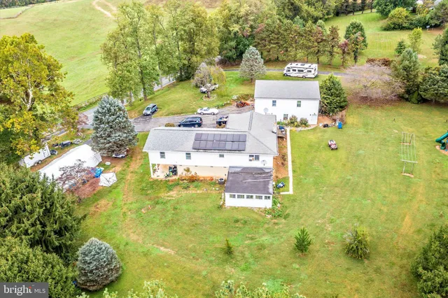a view of a white house with a big yard and large trees