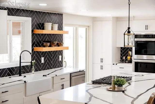 a kitchen with stainless steel appliances a white stove top oven a sink a dining table and chairs with wooden floor