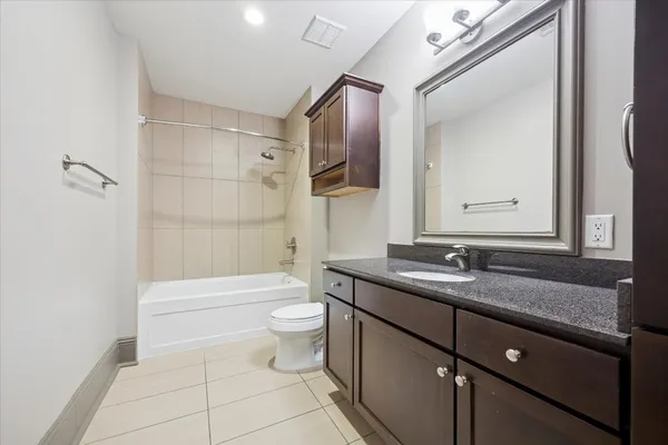 a bathroom with a granite countertop sink mirror vanity and toilet