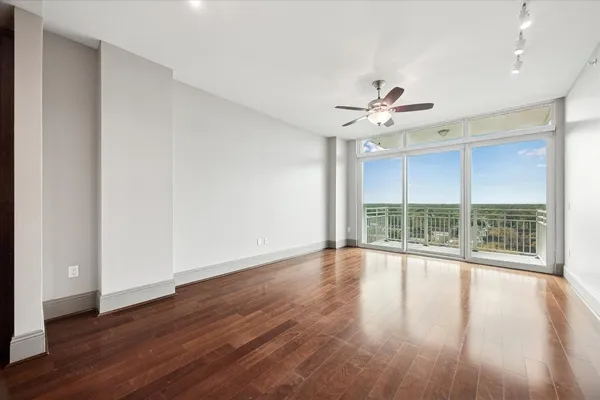 a view of an empty room with wooden floor and a window
