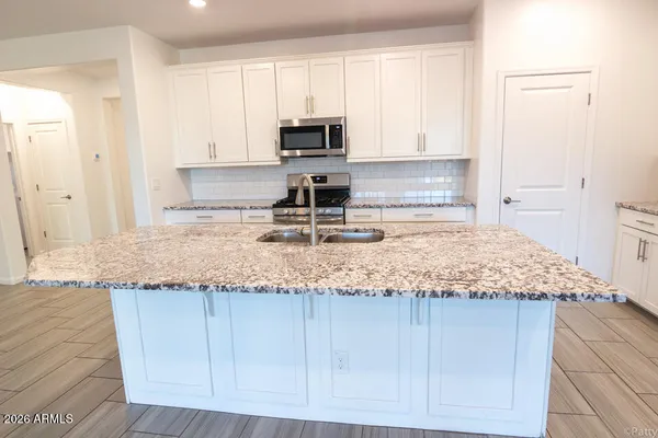 a kitchen with granite countertop a sink a stove and a microwave