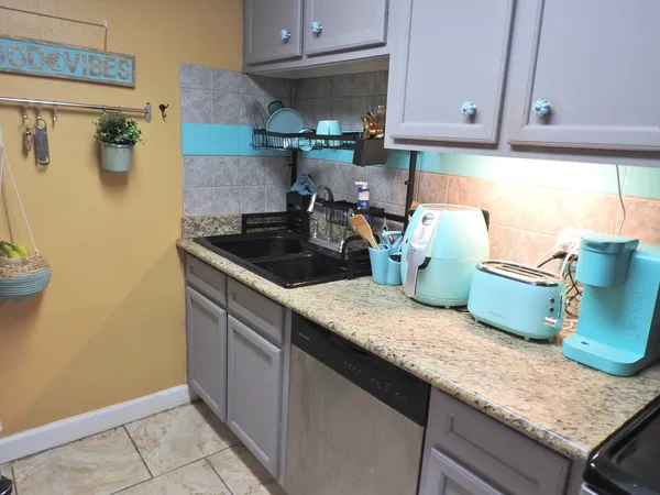 a kitchen with granite countertop a sink a stove and a wooden cabinets