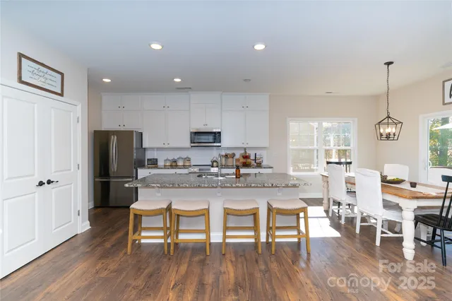 a kitchen with stainless steel appliances a refrigerator a stove a microwave and dining table