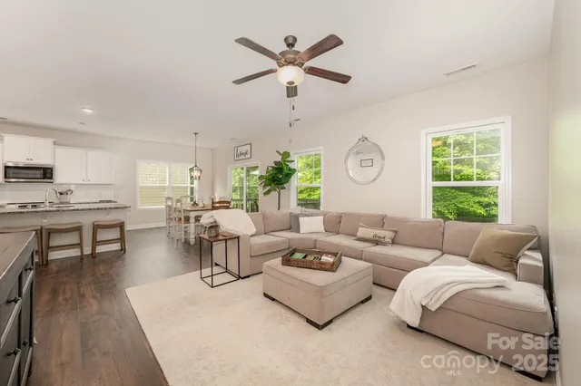 a kitchen with stainless steel appliances granite countertop a stove top oven a sink a dining table and chairs with wooden floor